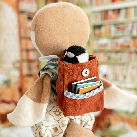 Lucy Owl wearing book bag for dolls, which has several books and a mini chickadee in the pockets