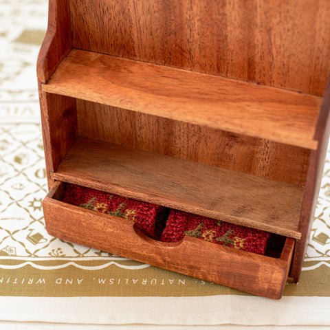 closeup of open drawer in bookshelf for dolls
